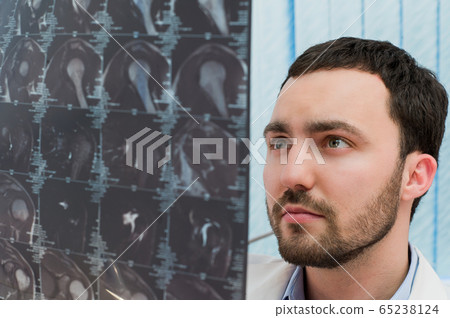 Medical office - portrait of middle-aged male doctor looking at computer tomograph scan. Medical office - portrait of middle-aged male doctor looking at computer tomograph scan. 65238124