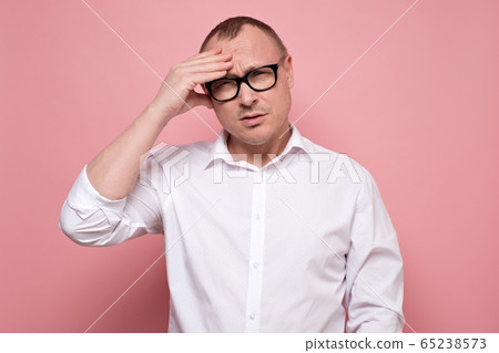 Stressed young man in eyeglasses regretting about something, looking at camera. 65238573