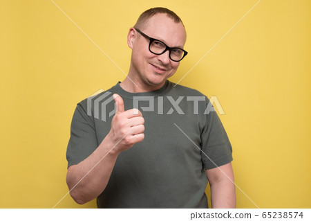 mature man gesturing thumb up approving your choice on yellow wall. 65238574