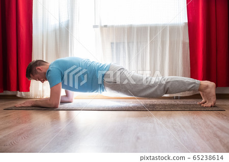 young man doing planking exercise at his living room at home. 65238614