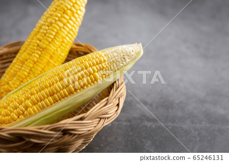 Raw corn in the basket on the black table 65246131
