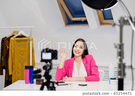 A female beauty blogger records a video in a white room. Lighting and camera on a tripod. A female beauty blogger records a video in a white room. Lighting and camera on a tripod. 65254471