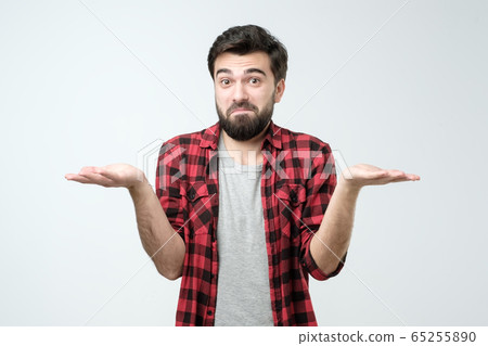 Confused hispanic man giving I dont know gesture on white background. Confused hispanic man giving I dont know gesture on white background. 65255890