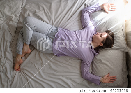 Young caucasian woman working out at home at the bed doing Spinal Twist 65255968