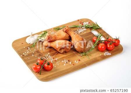 Cooked smoked chicken is on a cutting wooden board on a white background. Decorated with herbs and vegetables. 65257190