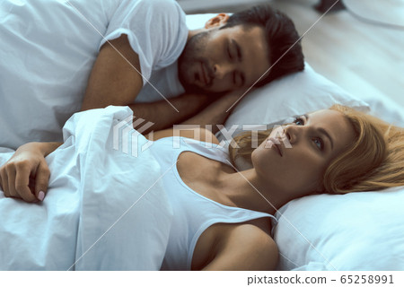 Young pretty woman waking up near asleep man 65258991