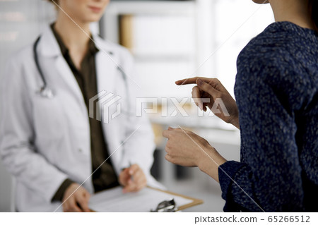 Doctor and patient discussing current health examination while sitting in clinic. Perfect medical service in hospital. Medicine concept Doctor and patient discussing current health examination while sitting in clinic. Perfect medical service in hospital. Medicine concept 65266512