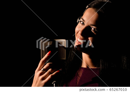 Portrait of young woman recording a song in a professional studio Portrait of young woman recording a song in a professional studio 65267010