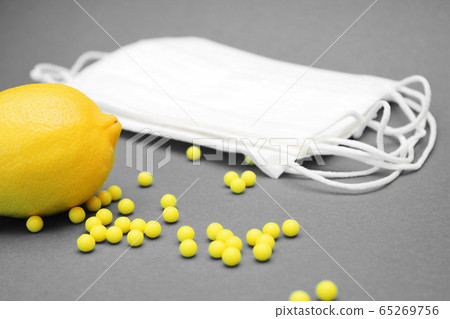 Lemon next to medical masks and a number of ascorbic acid vitamins 65269756