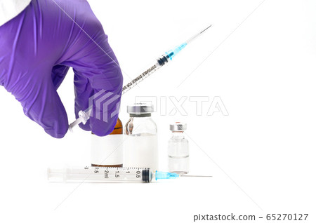 Pharmaceutical Scientist picking up a syringe. Coronavirus vaccine research. Medicine vials in white 65270127