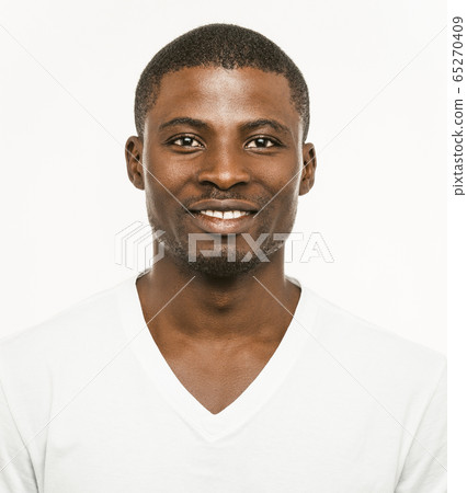 Positive Afro American man Smiles looking at camera. Portrait of dark-skinned cheerful man in white t-shirt isolated on white background. Front view 65270409
