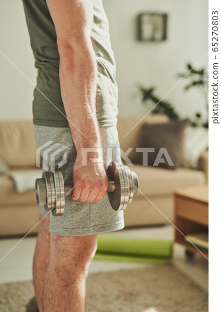 Middle section of young sportsman in activewear exercising with barbells Middle section of young sportsman in activewear exercising with barbells 65270803