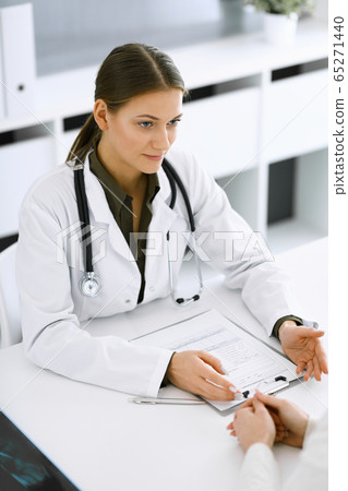 Woman-doctor and patient sitting and talking at hospital office. Green color blouse suits to therapist. Medicine and healthcare concept 65271440