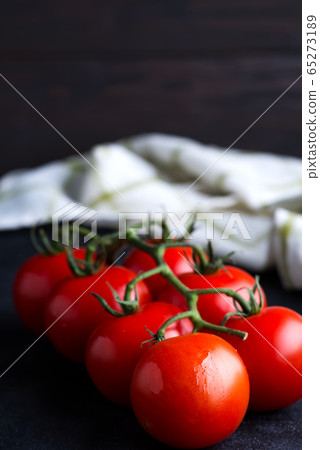 Fresh ripe organic tomatoes branch on a dark background with textile towel. 65273189