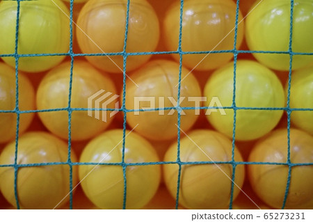 Yellow plastic balls behind the green net. 65273231