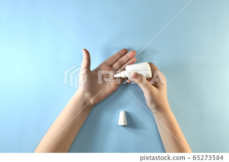The hand squeezes the transparent gel from the The hand squeezes the transparent gel from the 65273584