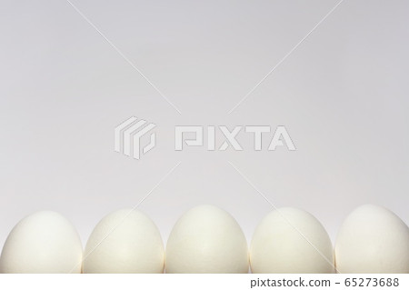 White chicken eggs lined up in a row half peeping White chicken eggs lined up in a row half peeping 65273688