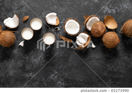 Coconut milk, whole and cracked coconuts on black 65273990