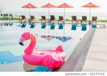 Flamingo float around swimming pool in hotel resort with umbrella and chair in hotel resort 65277219