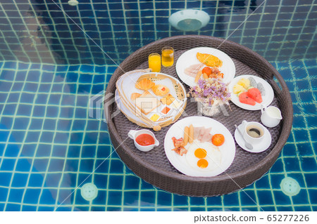 Breakfast set floating around swimming pool Breakfast set floating around swimming pool 65277226
