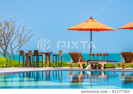 Umbrella and chair around outdoor swimming pool neary sea in hotel resort Umbrella and chair around outdoor swimming pool neary sea in hotel resort 65277363