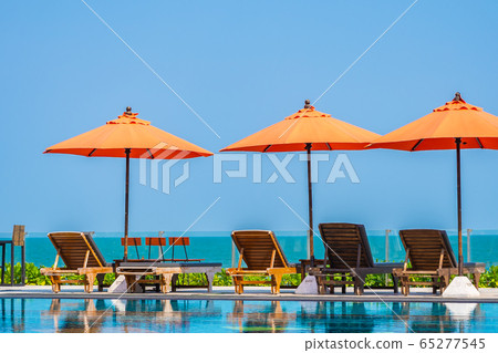 Umbrella and chair around outdoor swimming pool neary sea in hotel resort Umbrella and chair around outdoor swimming pool neary sea in hotel resort 65277545