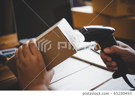 Delivery staff scanning cardboard box with barcode 65280493