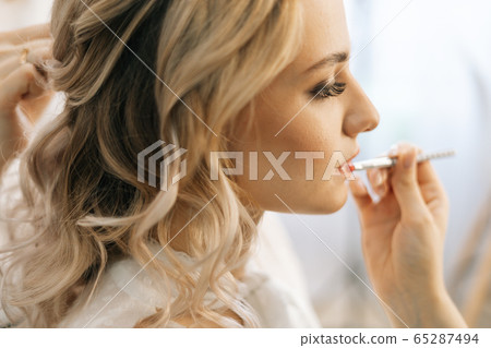 Close-up of professional make-up artist making makeup young woman lips with lip pencil 65287494