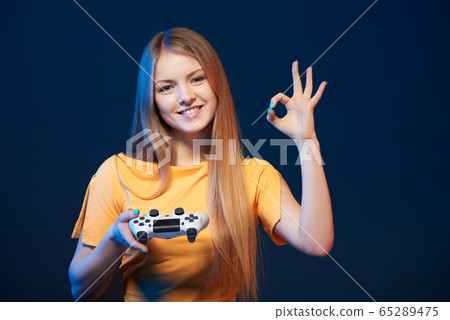 Happy girl holding video game joystick showing OK sign Happy girl holding video game joystick showing OK sign 65289475