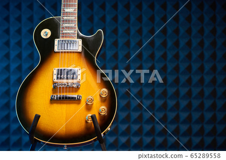 Sunburst electric guitar standing over acoustic foam panel background Sunburst electric guitar standing over acoustic foam panel background 65289558