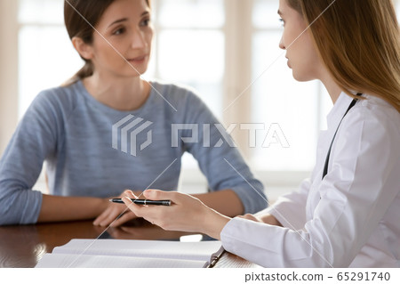 Female doctor discuss checkup results with patient at consultation Female doctor discuss checkup results with patient at consultation 65291740