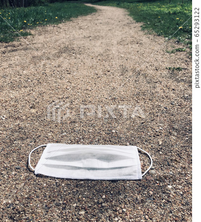 A white medical mask used to fight the coronavirus was left on the road. 65293122
