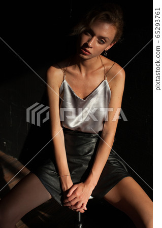 Portrait of a beautiful fashionable blonde woman on a black office couch in the room Portrait of a beautiful fashionable blonde woman on a black office couch in the room 65293761