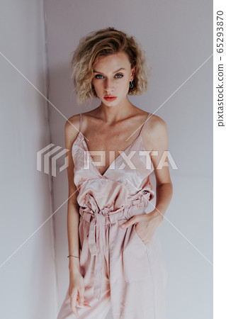 Beautiful fashionable blonde woman in pink silk dress on a gray background 65293870