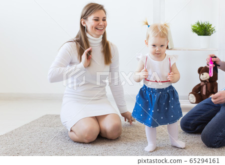 Hearing aid in baby girl's ear. Toddler child wearing a hearing aid at home. Disabled child, disability and deafness concept. 65294161