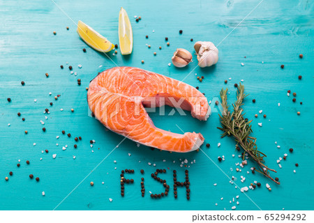 Salmon with lemon, pepper and rosemary on blue background top view and the inscription pepper fish. Keto diet, pescetarianism and healthy food concept. Salmon with lemon, pepper and rosemary on blue background top view and the inscription pepper fish. Keto diet, pescetarianism and healthy food concept. 65294292