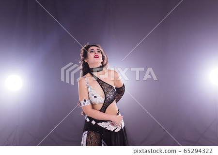 Young woman belly dancer in exotic dress with gold, dancing tribal fusion dance in studio. Young woman belly dancer in exotic dress with gold, dancing tribal fusion dance in studio. 65294322