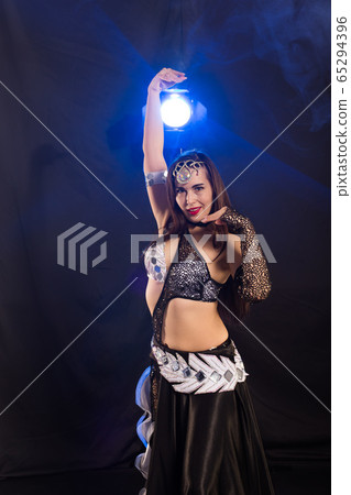 Girl dancing belly dance, fusion or tribal. A woman in a beautiful costume demonstrates charming and gentle movements in the dance. 65294396