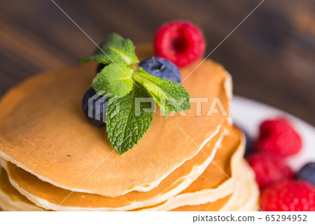 Pancakes with blueberries and raspberry on wooden background. Breakfast and traditional meal. Pancakes with blueberries and raspberry on wooden background. Breakfast and traditional meal. 65294952