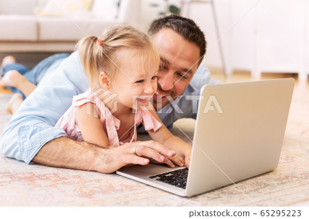 Dad and daughter watching cartoons at home 65295223