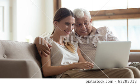 Happy senior dad and adult daughter using laptop together Happy senior dad and adult daughter using laptop together 65295318