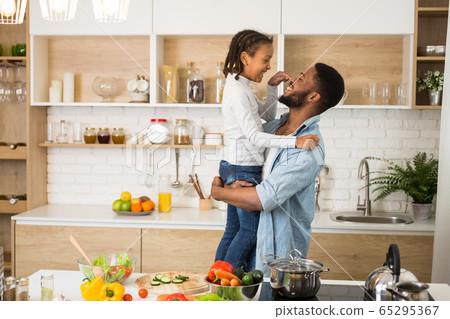Little girl and cheerful father bonding at kitchen 65295367
