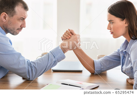 Business Man And Woman Arm Wrestling At Work In Office 65295474