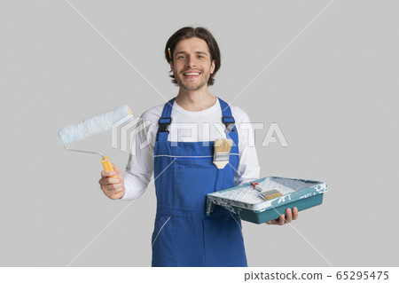 Renovation Services. Smiling Painter In Uniform With Painting Tools In Hands Renovation Services. Smiling Painter In Uniform With Painting Tools In Hands 65295475