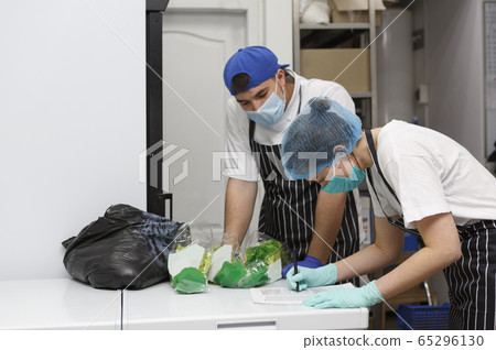 Woman in mask and gloves checking products list, take away 65296130