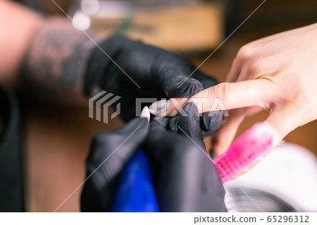 Close-up of hardware milling cutter for removing gel polish. Apparatus manicure in beauty salon. Manicurist with electric nail drill remove old gel from client nails. Process of replacing old shellac. 65296312