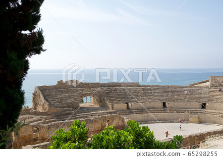 TARRAGONA, SPAIN - AUG 28th, 2017: a panoramic view of the ancient roman amphitheater next to the Mediterranean sea TARRAGONA, SPAIN - AUG 28th, 2017: a panoramic view of the ancient roman amphitheater next to the Mediterranean sea 65298255