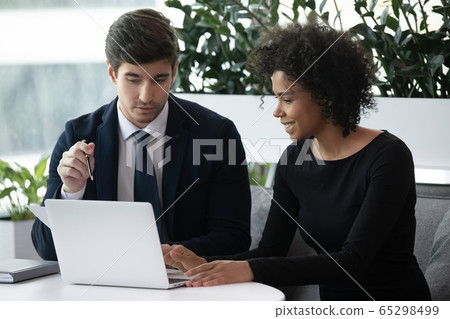 African businesswoman Caucasian businessman discussing project using laptop African businesswoman Caucasian businessman discussing project using laptop 65298499