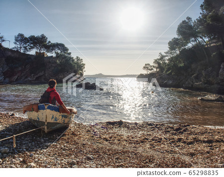 Woman sitting in wrecked boat  and enjoy sunbathing. The pebles  bank  65298835