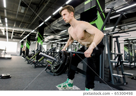 strong bodybuilder athletic man pumping up muscles workout bodybuilding concept background - muscular bodybuilder handsome man doing exercises in gym naked torso 65300498